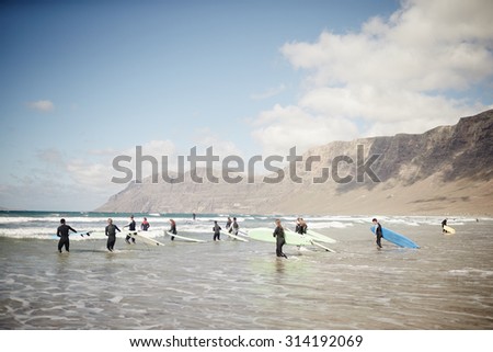 FAMARA BEACH, LANZAROTE ISLAND - APRIL 15. 2015: Group surf lesson. Newcomers are entering the water.