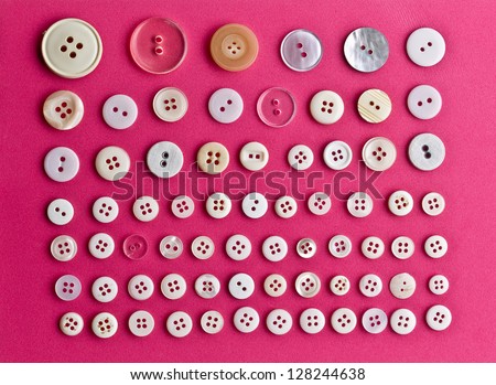 collection of various buttons on pink concrete background