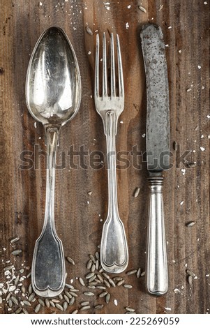 Vintage silver knife, fork and spoon on a rustic weathered table.