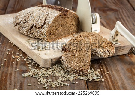Rye bread on old cutting board / slicer  on wooden background