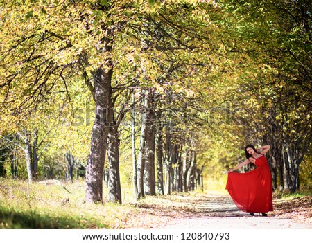 beautiful brunette woman wearing red long bright dress in the forest. attractive slim caucasian sexy girl with brown hair at autumn day outdoor. series