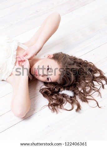 Portrait of a beautiful High fashion young woman lying on the white wood floor