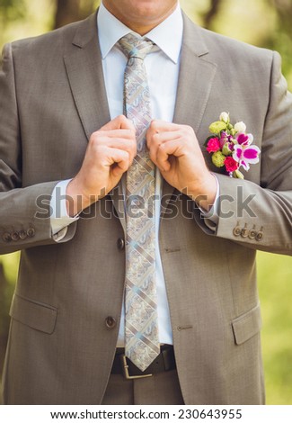 A groom putting on cuff-links as he gets dressed in formal wear
