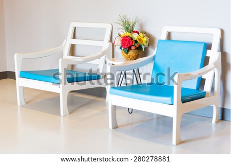 Double vintage armchairs with blue cushion and also flower in the jar between them