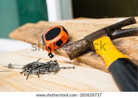 Carpentry tools include nails, hammer and measurement tape focusing on a group of nails.