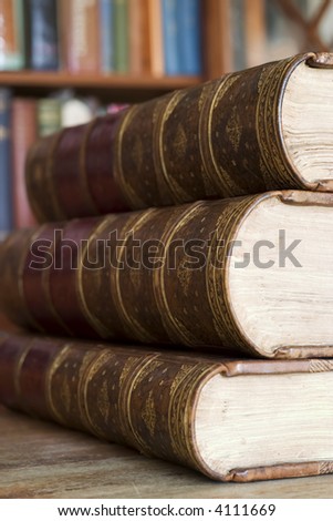 Three old books in front of library shelves