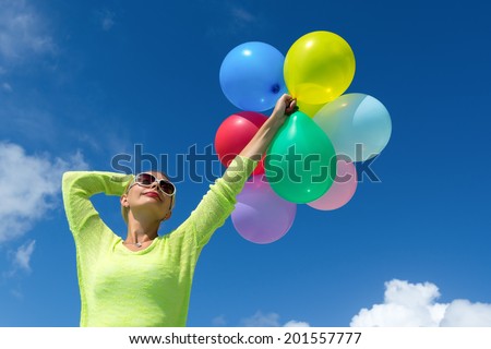 Woman holding balloons against cloud and sky