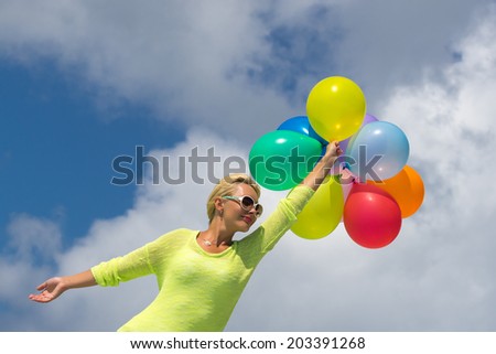 Woman holding balloons against cloud and sky