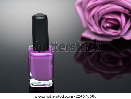violet nail polish and rose on a black background