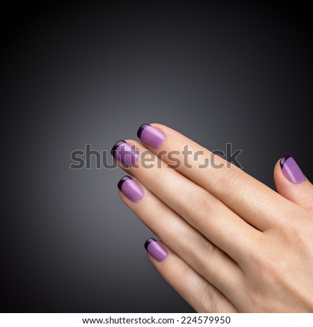 Beautiful manicure, polish is a violet color. Black background closeup.