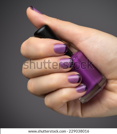 Beautiful manicure and polish is a violet color. Black background closeup.