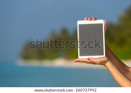 Concept of internet and communication. blank empty tablet computer in the hands of women on the beach