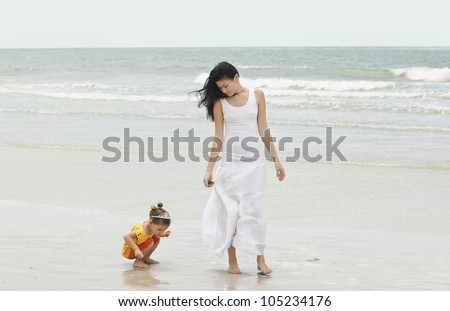 Mother and daughter walking along tropical beach