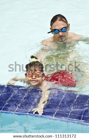 Father and daughter playing in the pool.