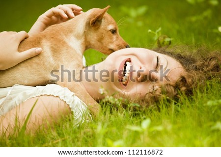 Happy woman lying on the grass with her dog in the park
