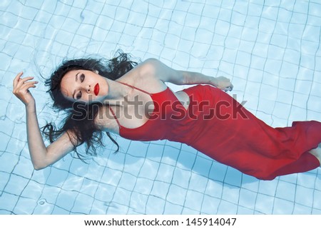 Female in a red dress swimming in the pool