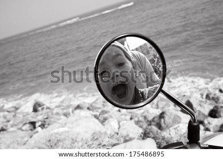 Kid\'s reflection in the motorbike\'s mirror