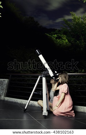 Girls looking at the moon through a telescope