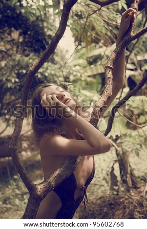 A girl in a bathing suit wraps her slender body tree