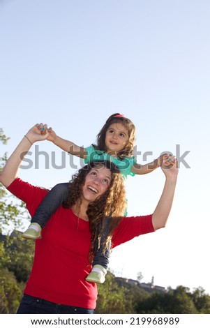 Teenage Girl Giving Toddler a Shoulder Ride Outside with Copy Space