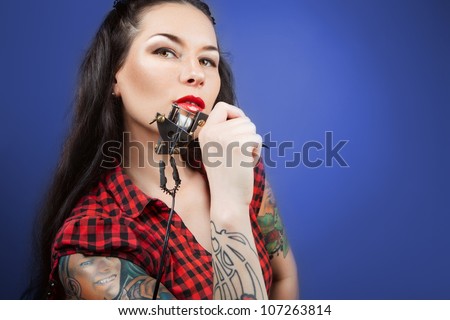 Photo of beautiful girl with tattoos and tattoo machine. tattoo machine