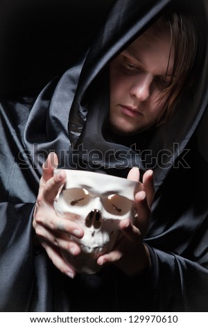 young man with human skull in the hand. skull