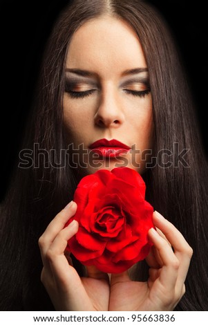 close-up portrait of beautiful brunette woman with red rose. dark background