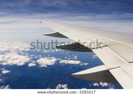 Blue sky and land view over the wing of the plane.