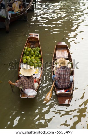 Two peasants in the boat sells their coconuts at at the floating market near Bangkok, Thailand. The floating market is in Damnoen Saduak near Bangkok, Thailand.