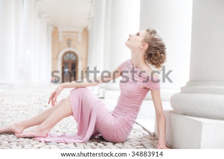fashion shot of a young woman sitting near columns in old mansion