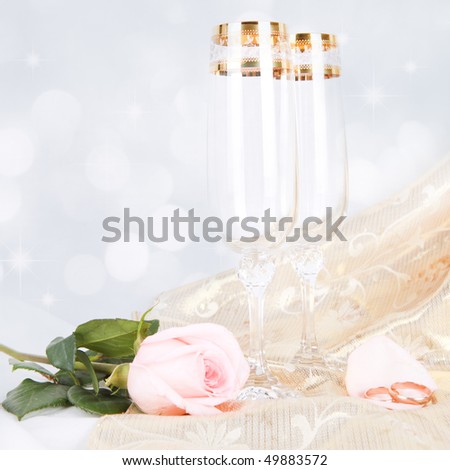 two glasses of champagne with rose over gold background with bokeh