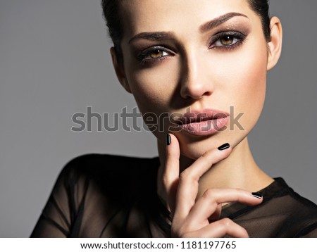 Face of a beautiful girl with smoky eyes makeup posing at studio over dark background