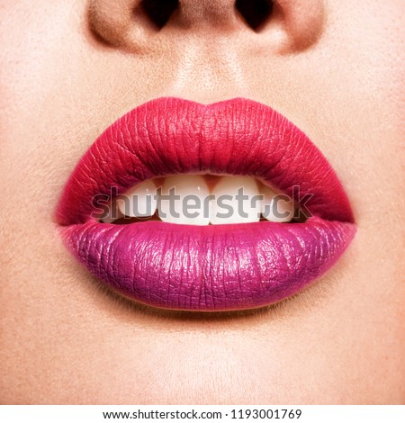Close up view of beautiful woman lips with purple red and purple lipstick. Open mouth with white teeth.  fashion makeup concept. Beauty studio shot.