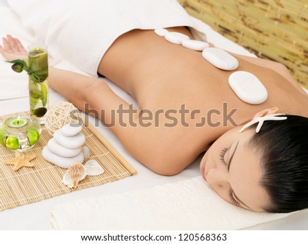 Stone massage for young woman at beauty spa salon. Recreation therapy.