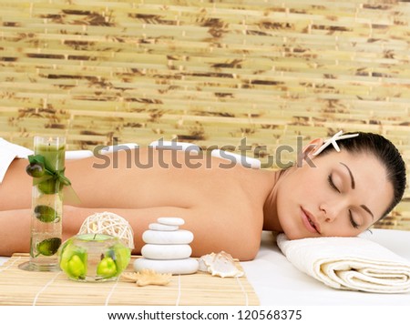 Stone massage for young woman at beauty spa salon. Recreation therapy.