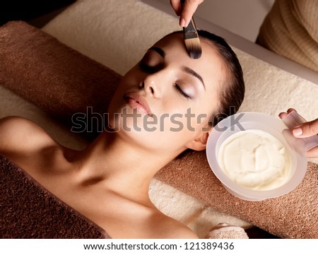 Spa therapy for young woman receiving facial mask at beauty salon indoors Spa therapy for young woman receiving facial mask at beauty salon indoors
