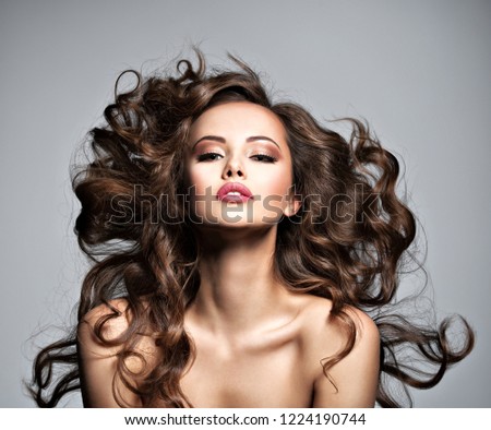 Beautiful  woman with long brown curly hair. Portrait of a pretty young  girl with flying hair