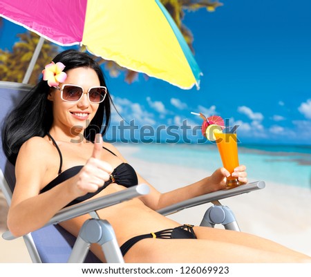 Happy brunette woman on vacation at beach with thumbs up sign