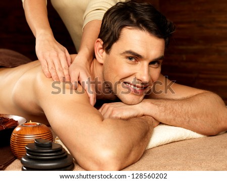 Masseur doing massage on smiling man body in the spa salon. Beauty treatment concept.