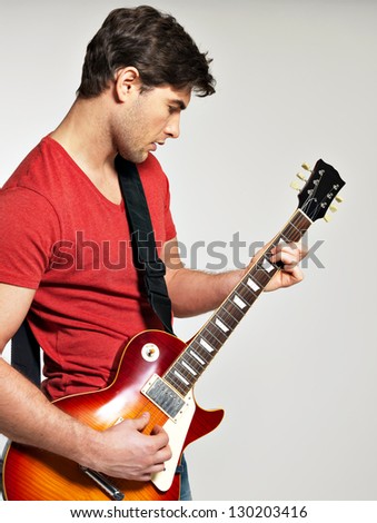 Guitarist plays on the electric guitar with bright emotions on grey  background