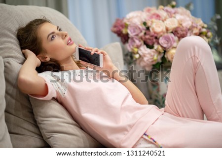 Happy young woman talking by smart phone at home. Attractive woman calling by phone  indoors.