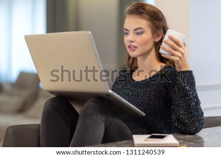 Attractive  woman with computer at home. Caucasian woman working on computer indoors.