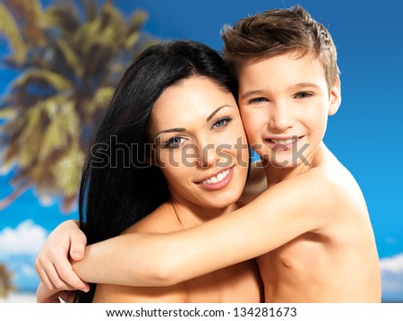 Portrait of  happy smiling mother hugs son 8 years old at tropical beach