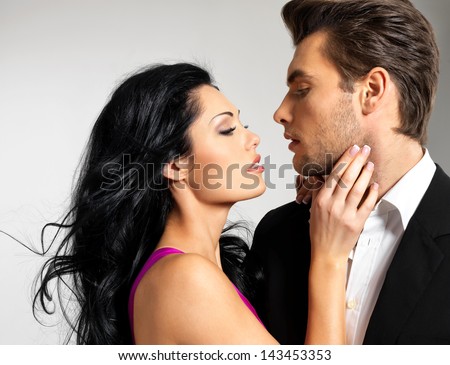Portrait of young couple in love posing at studio dressed in classic clothes