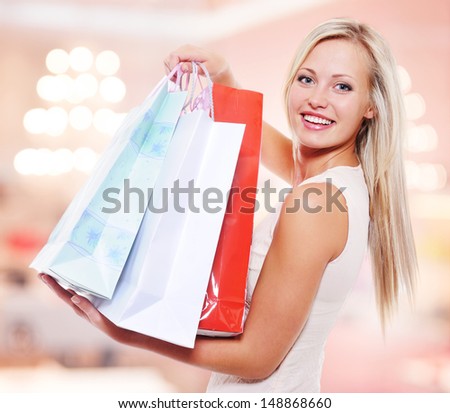 Happy beautiful woman with shopping bags stands at shop