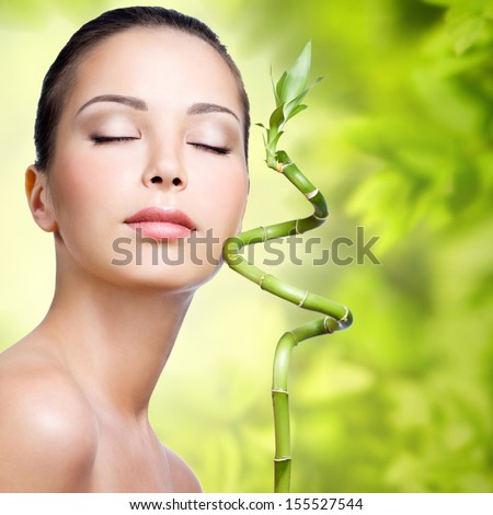 Closeup healthy face of young woman with sprout in hands over nature green background