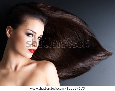 Young woman with long brown straight hairs on a dark background