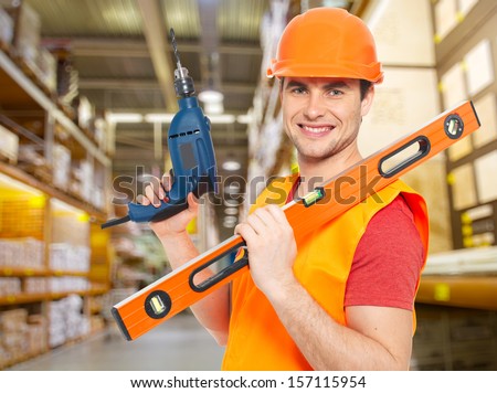 Portrait of smiling manual worker with tools at warehouse