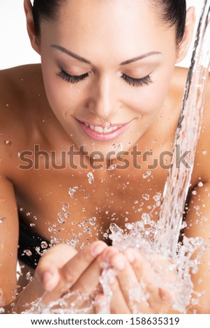 Closeup portrait of a smiling woman washing her clean face with water