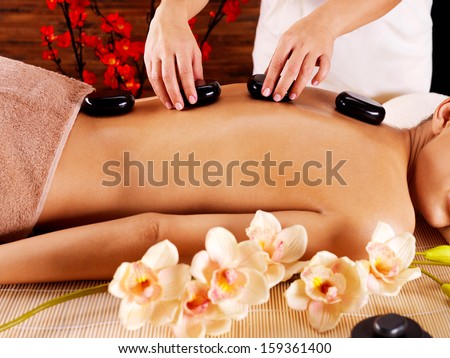 Photo of a woman\'s body with  hot stones on back  massage in spa salon. Beauty treatment concept.